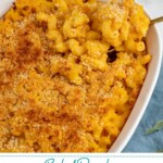 Pinterest pin with text overlay "Baked Pumpkin Mac & Cheese", image of a white casserole dish with a serving spoon scooping out Mac and cheese.