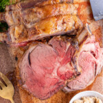 Pinterest Pin with logo overlay 'the Schmidty wife', image os a cut of prime rib up against a large prime rib roast on a cutting board.