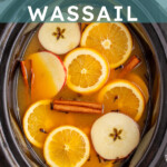 Pinterest Pin with text overlay 'Crockpot Christmas Wassail', image of a crockpot and mugs filled with wassail and garnished with orange slice and spices.