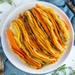 Pinterest Pin with logo overlay "The Schmidty Wife", image showing a colorful savory tarte tatin with lines of root vegetables displayed on a plate.