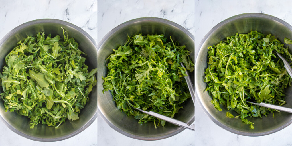 Dressing arugula in a bowl with tongs.