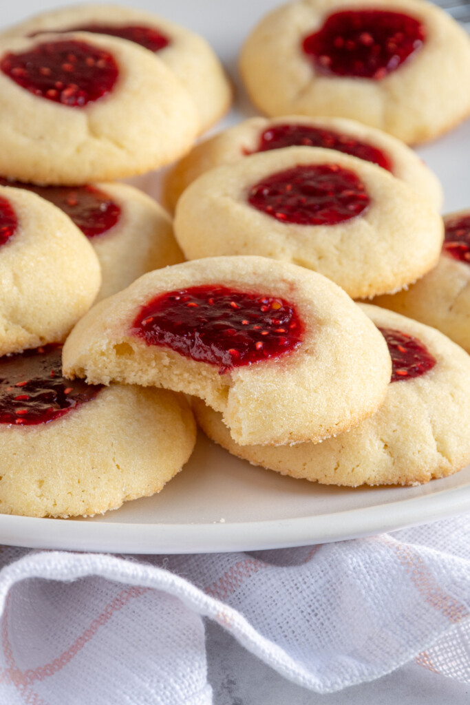 Close up of a raspberry thumbprint cookie with a bite taken out of the soft dough.