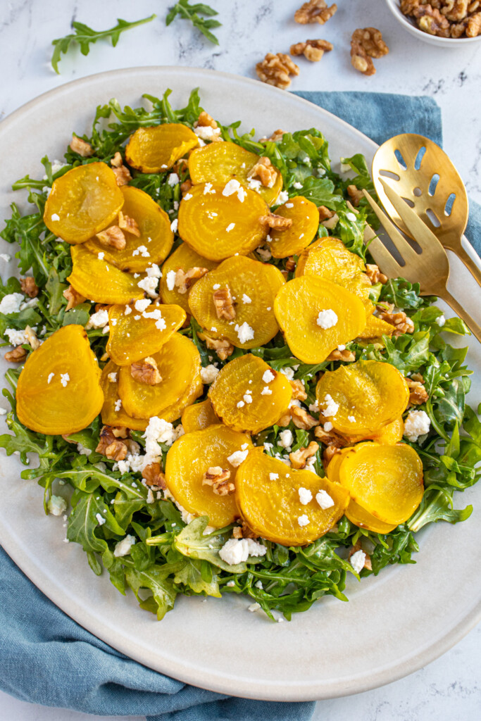 A platter filled with arugula and topped with roasted beets, walnuts, and feta.