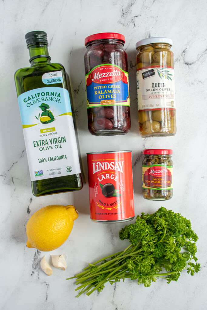 Ingredients needed to make olive tapenade including black, green, and Kalamata olives.