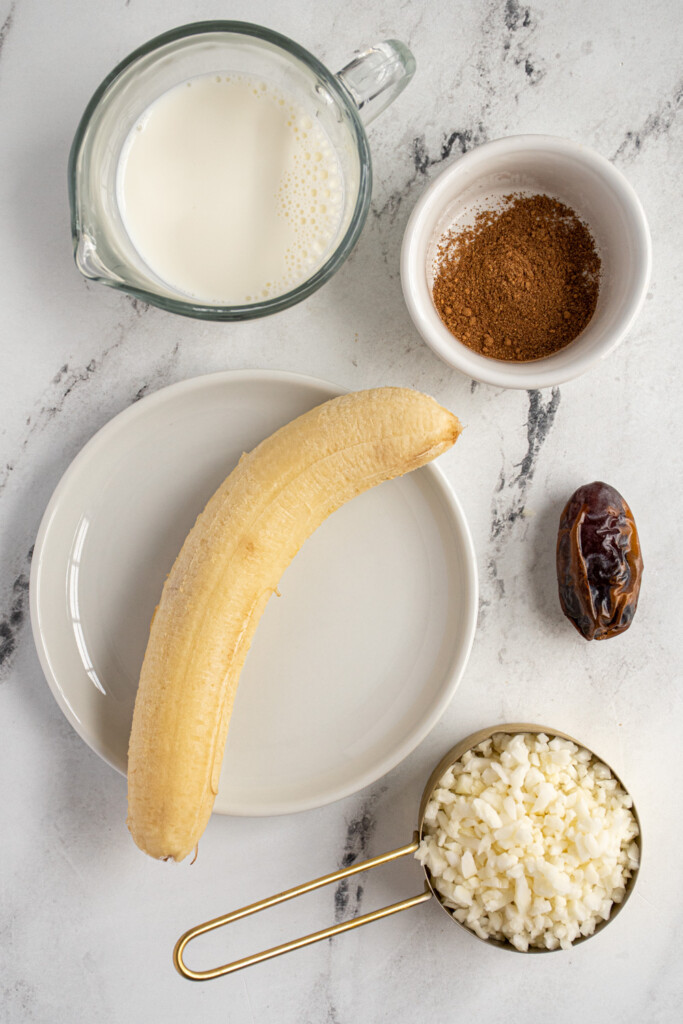 Ingredients needed to make a banana chai smoothie laid out on a table top.