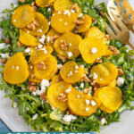 Pinterest pin with text "Golden Beet & Arugula Salad", image of a platter of arugula with roasted beets, walnuts, and feta cheese.