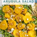 Pinterest pin with text "Golden Beet & Arugula Salad", image of a platter of arugula with roasted beets, walnuts, and feta cheese.