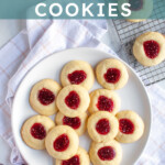 Pinterest pin with text overlay 'Raspberry Thumbprint Cookies', image of a plate of raspberry thumbprint cookies, the center one has a bite taken out.