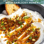 Pinterest pin with text overlay 'Whipped Feta with Garlicky Honey', image of a bowl with whipped feta dip and honey.