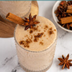 Pinterest pin with test overlay 'Banana Chai Smoothie', image of a glass filled with a light brown banana chai smoothie with garnishes.