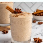 Pinterest pin with test overlay 'Banana Chai Smoothie', image of a glass filled with a light brown banana chai smoothie with garnishes.