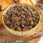 Pinterest Pin with text overlay 'Olive Tapenade', image of a yellow and white bowl filled with freshly made olive tapenade.