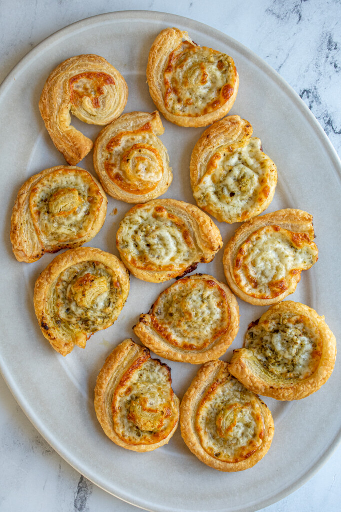 A white platter filled with pesto pinwheels.