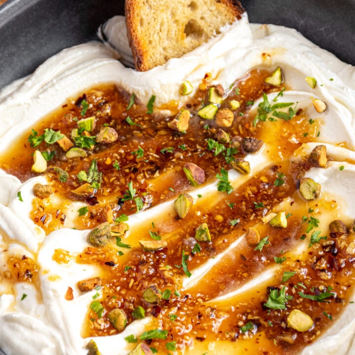 Close up of whipped feta in a bowl with honey and garnished with pistachios and parsley.