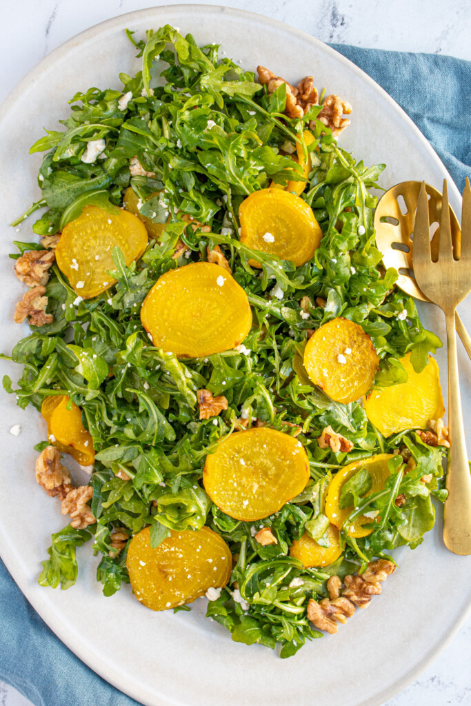 A platter of arugula tossed with feta, walnuts, and golden beets.