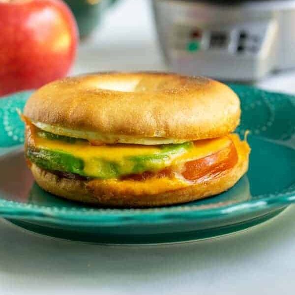Avocado breakfast sandwich sitting on a teal plate.