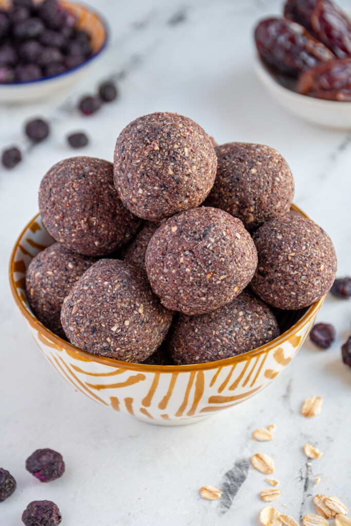 Close up of purple blueberry energy balls in a bowl.