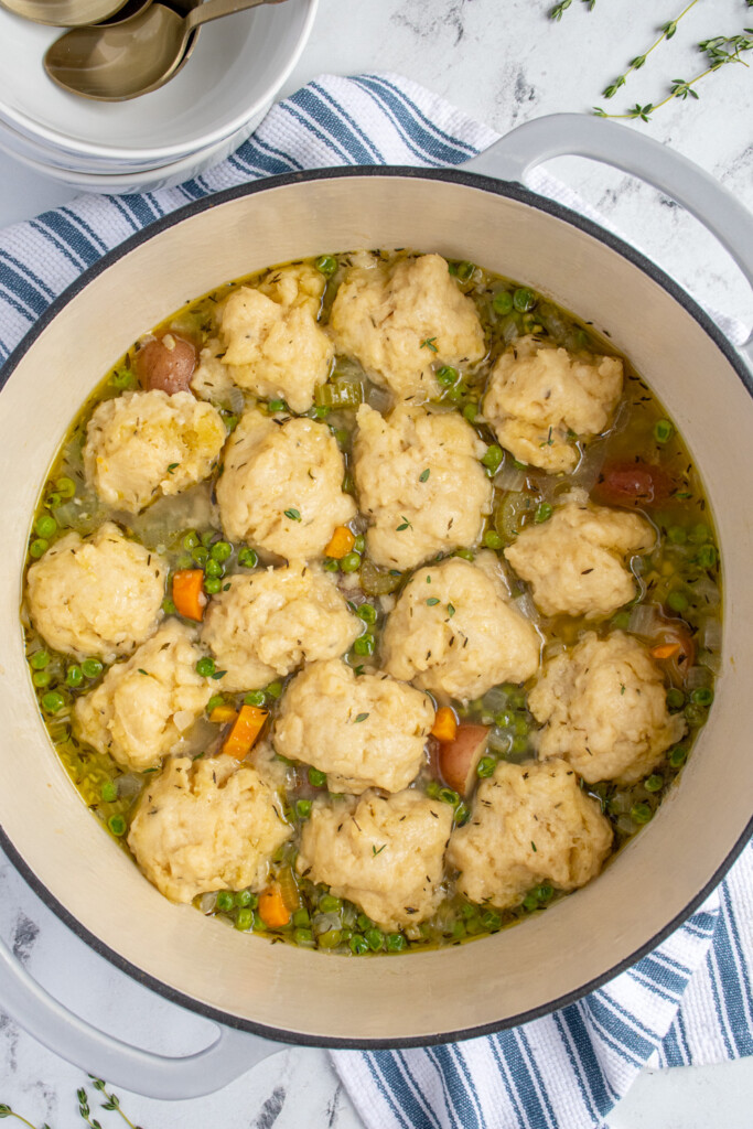 Close up of a dutch oven filled with veggie soup topped with American dumplings.
