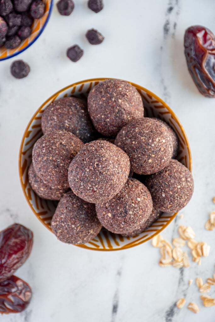 Overhead view of a bowl filled with purple colored blueberry energy balls.