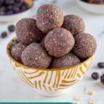 Pinterest Pin with text overlay "Blueberry Energy Balls", image of a bowl of purple blueberry energy balls.
