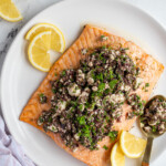 Pinterest pin wit logo overlay "The Schmidty Wife" with image of a plate of salmon topped with olive tapenade.