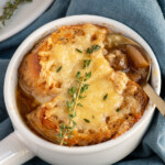 Pinterest pin with logo overlay 'the Schmidty wife', image of a white bowl filled with French onion soup and topped with baguette and melted cheese.