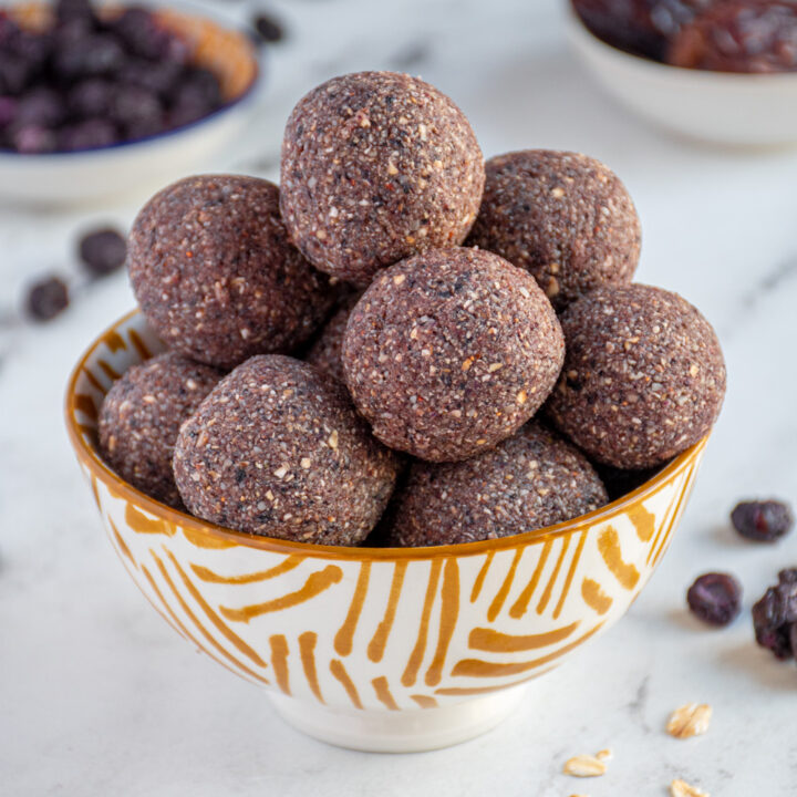 White and yellow bowl filled with purple blueberry energy balls.