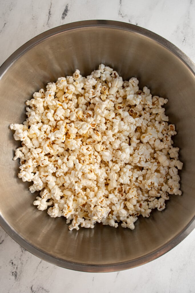 Big stainless steel bowl full of freshly popped popcorn on the stovetop.