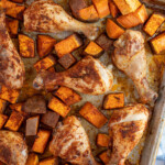 Pinterest pin with logo overlay "The Schmidty Wife", image of a sheet pan with baked chicken legs and sweet potatoes.