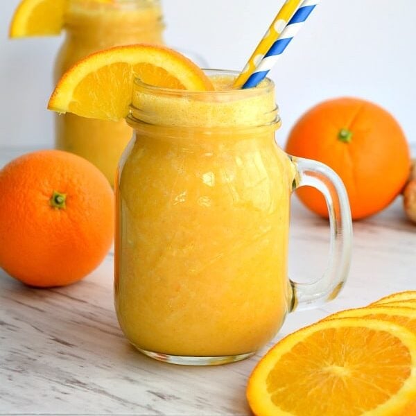 2 orange ginger sunshine smoothies with oranges and orange slices