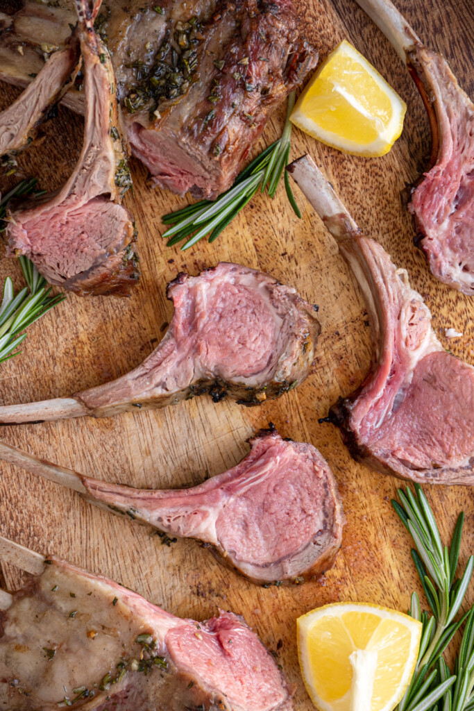Cut grilled rack of lamb cut and spread out over a wooden cutting board.