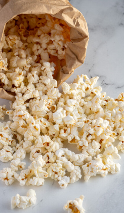 Popcorn cascading out of a brown paper bag after being cooked in the microwave.