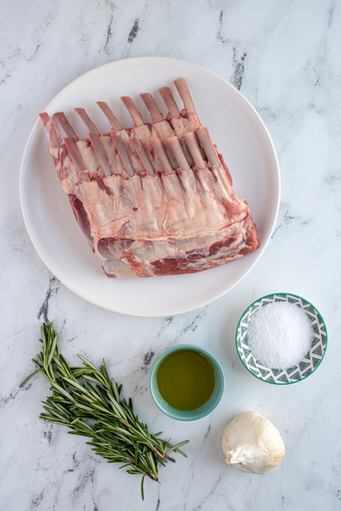 Ingredients needed to make grilled rack of lamb laid out on a marble table top.