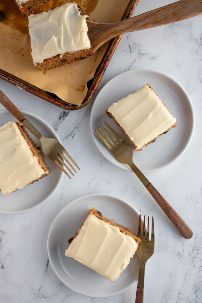 Overhead view of square slices of carrot cake on many different plates.