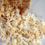 Pinterest pin with "The Schmidty Wife" logo, image of a brown bag with popcorn tumbling out onto a table top.