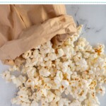 Pinterest pin with text overlay "Paper Bag Microwave Popcorn", image of a brown bag rolled up and popcorn tumbling out onto a tabletop.