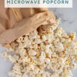 Pinterest pin with text overlay "Paper Bag Microwave Popcorn", image of a brown bag rolled up and popcorn tumbling out onto a tabletop.