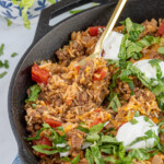 Pinterest pin with logo overlay "The Schmidty Wife" with image of taco rice skillet made in a cast iron.