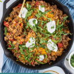 Pinterest pin with text overlay "Taco Rice Skillet" with image of taco rice skillet made in a cast iron.