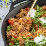 Pinterest pin with text overlay "Taco Rice Skillet" with image of taco rice skillet made in a cast iron.