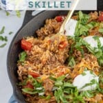 Pinterest pin with text overlay "Taco Rice Skillet" with image of taco rice skillet made in a cast iron.
