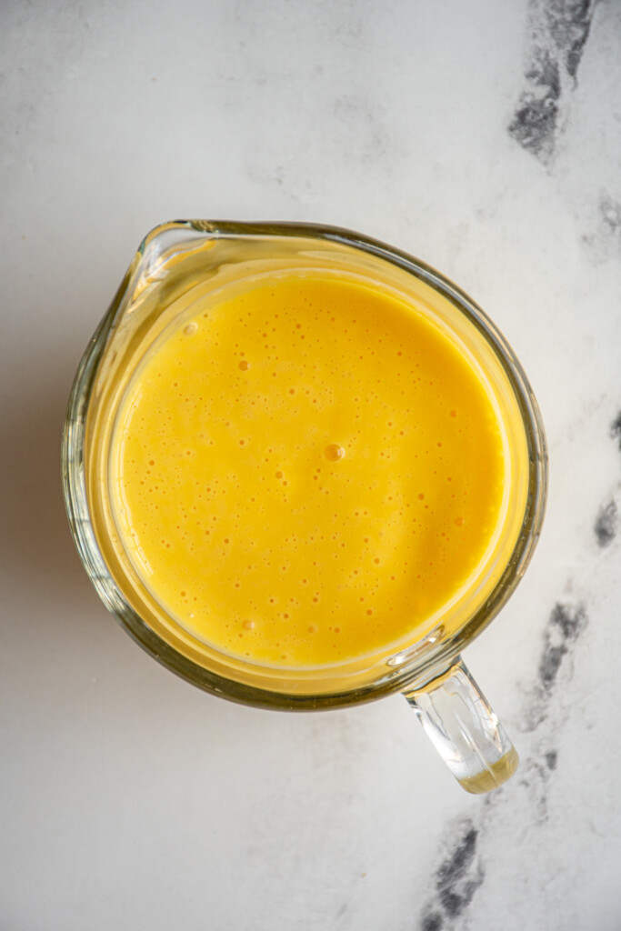 A serving glass filled with freshly made hollandaise.