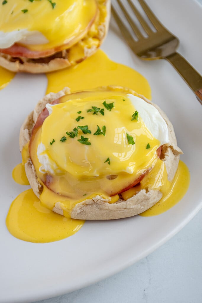 A close up of eggs Benedict on a white plate.