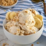A bowl filled with cottage cheese ice cream garnished with crushed peanuts and banana slices.