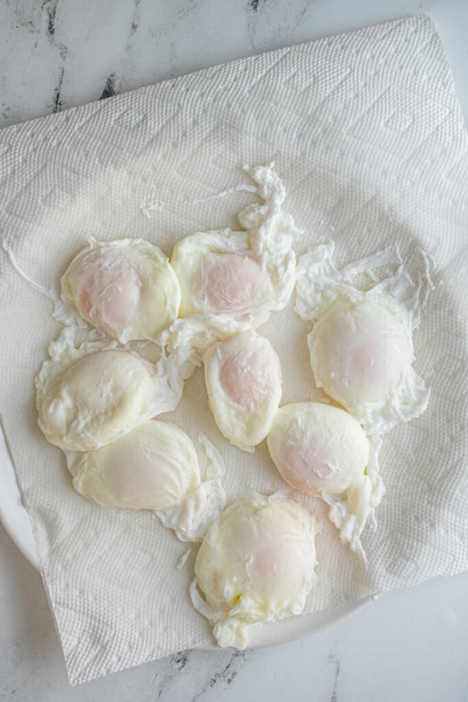Poached eggs on a paper towel lined plate.