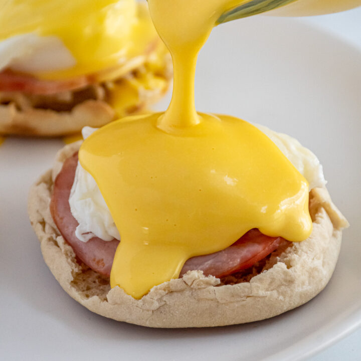 Blender hollandaise sauce being poured overtop a poached egg.