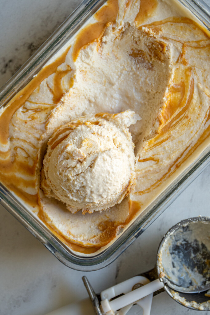 A container filled with cottage cheese ice cream with a scoop taken out sitting on top.