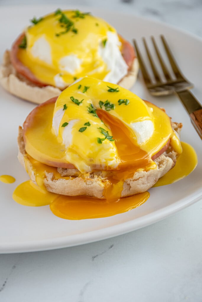 The poached egg broken open on an eggs Benedict.