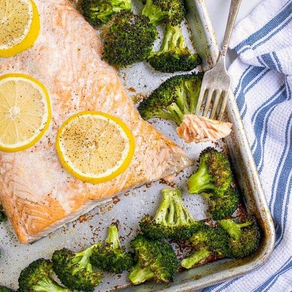 Forkful of baked salmon with broccoli on a sheet pan.