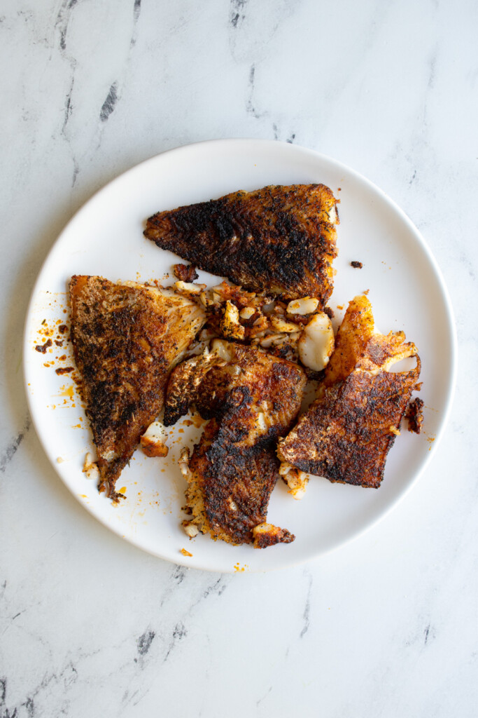A plate with cooked blackened fish.